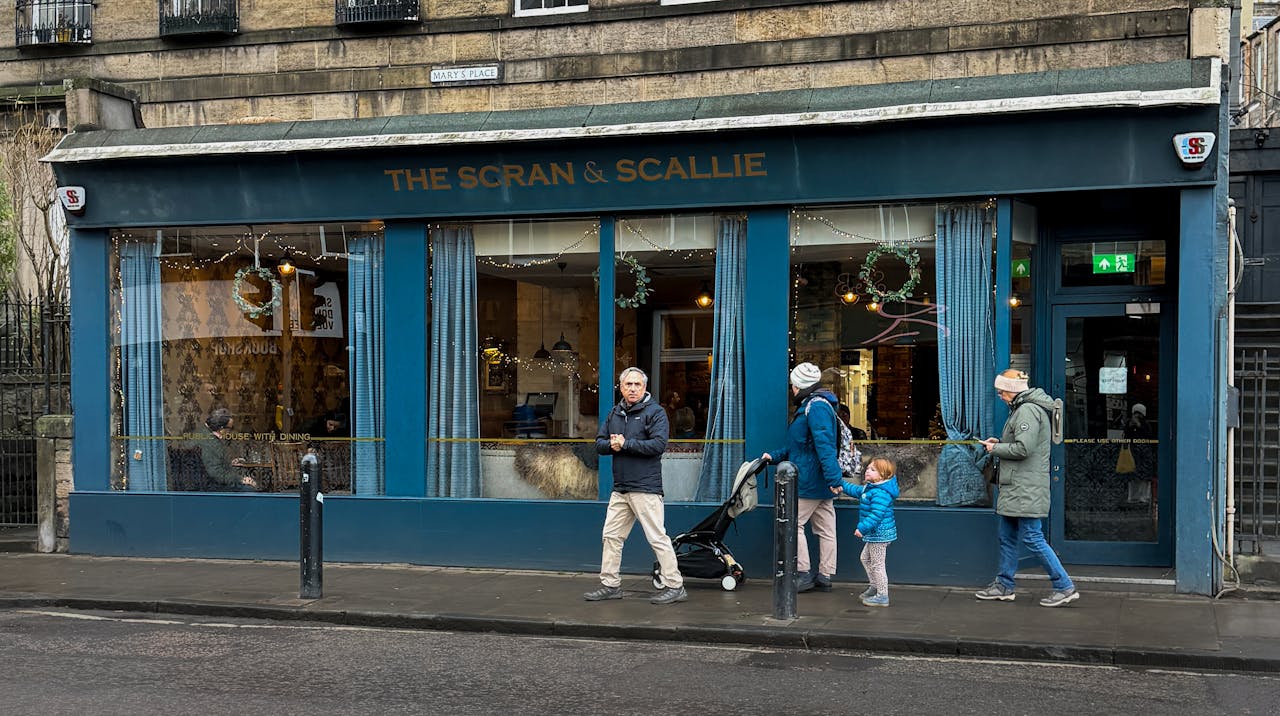 People walking outside The Scran & Scallie restaurant in Edinburghs charming cityscape.